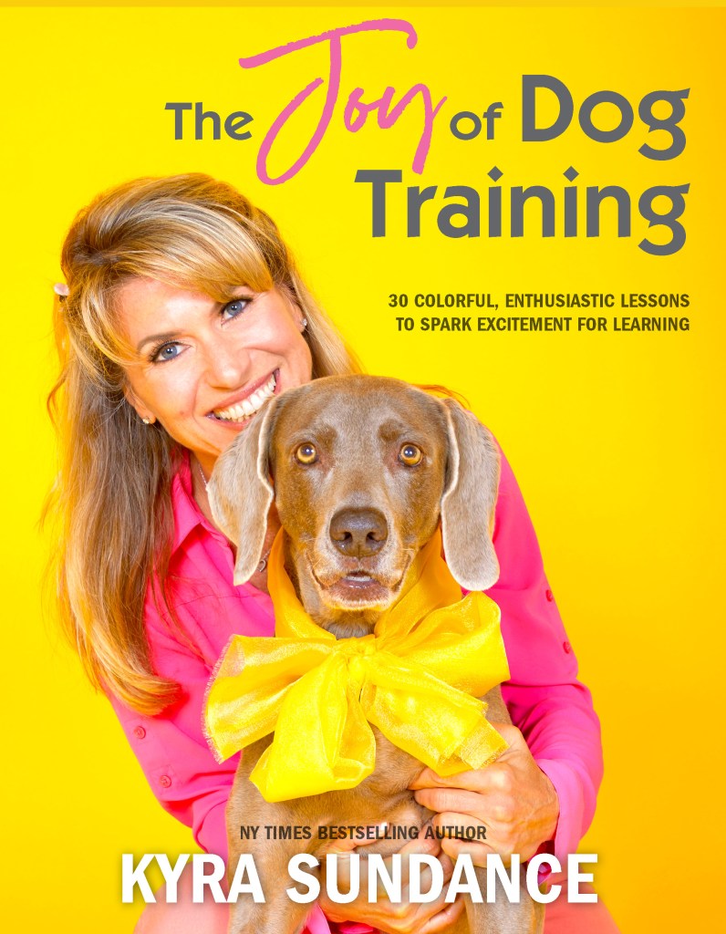 The cover of The Joy of Dog Training features the author in a hot pink blouse and her Weimaraner dog wearing a neon yellow bow. 